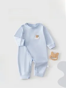 Detail of light blue cotton baby romper featuring a cute bear embroidery and snap closure