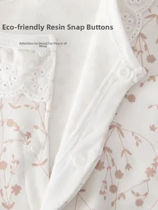Détail macro du body bébé à fleurs avec col en dentelle blanche et boutons-pression