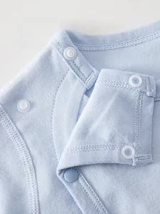 Detail of baby cotton jumpsuit featuring eco-friendly resin snap buttons for safety
