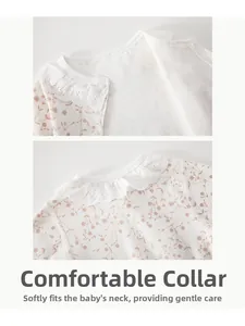 Détail d'un body bébé en coton à fleurs montrant le col en dentelle et le bouton pression