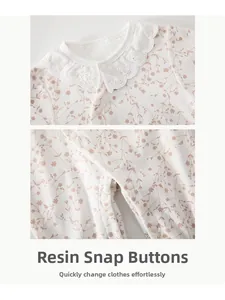 Détail d'une barboteuse bébé en coton fleuri montrant le col en dentelle et pressions