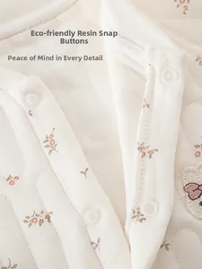 Détail des boutons-pression en résine sur une barboteuse matelassée fleurie pour bébé