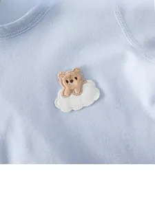 Detailed view of baby onesie featuring a 3D embroidered brown bear on a white cloud