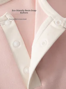 Detail of eco-friendly resin snaps and white piping on soft cotton baby clothing