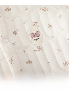 Détail d'une grenouillère matelassée pour bébé avec imprimé fleuri et broderie lapin