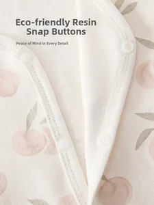 Détail d'un gilet bébé en coton avec imprimé cerise et boutons-pression en résine
