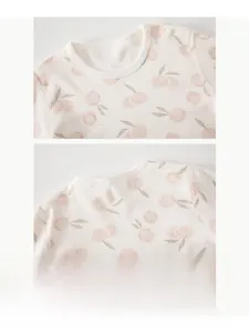 Detail of baby cotton sleepwear featuring cherry prints and shoulder snap buttons