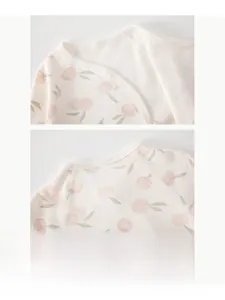 Dettaglio dello scollo della tutina in cotone per neonati con stampa a pesche e bottoni