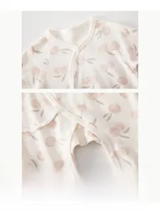 Dettaglio tutina per neonati in cotone con stampe di ciliegie rosa e bottoni in resina