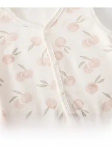 Détail du gilet en coton pour bébé avec motifs de pommes roses et boutons en résine