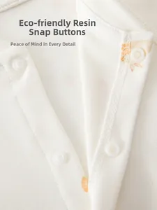 Détail macro des boutons-pression en résine sur une barboteuse bébé en coton pur