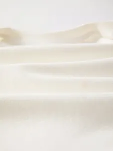 Gros plan sur le tissu en coton blanc cassé doux et respirant pour barboteuses de bébé
