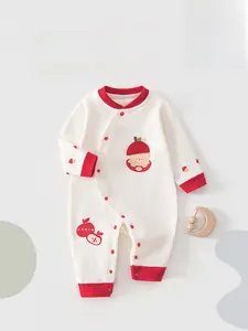 Detail eines Baby-Stramplers aus Baumwolle mit rotem Saum und Apfel-Stickerei