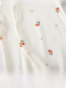Detailed view of soft cotton baby romper with orange hawthorn print and white snap buttons