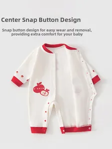 Detail of baby ivory cotton romper with red snap closure and apple graphic pattern