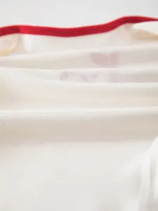 Close-up of soft fine-spun cotton fabric with red trim for newborn baby rompers