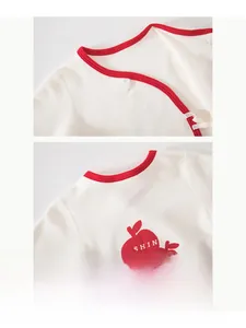Detail of baby cotton kimono romper with red apple print and soft side-snap neckline