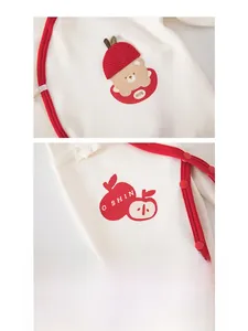 Macro view of newborn cotton romper featuring red apple prints and soft snap buttons