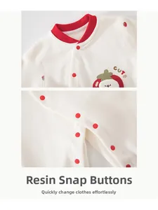 Detail of baby romper with strawberry embroidery and red resin snap buttons