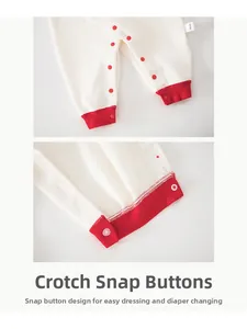 Close-up of cotton baby romper with red snap buttons and ribbed cuffs on soft fabric