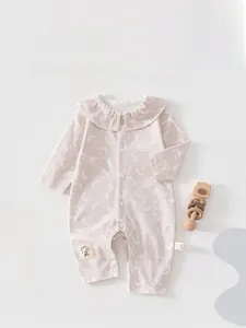 Detail of pink cotton baby romper featuring ruffled collar and crescent moon prints