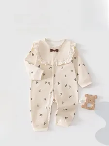 Detailed view of baby romper featuring bird print with ruffle collar and bow