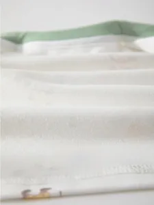 Macro shot of white breathable fine cotton fabric with soft texture and green edging
