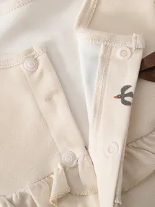 Detail view of eco-friendly resin buttons and bird print on cotton baby romper fabric