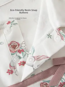 Detail of floral baby bodysuit featuring pink unicorn prints and resin snap buttons