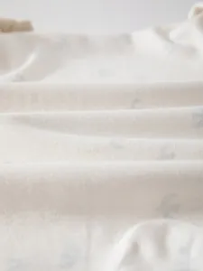 Close-up of soft cotton baby romper fabric with delicate bird pattern and breathable texture