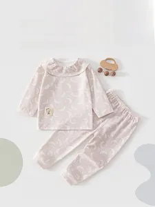 Close-up of pink infant pajama set with white moon patterns and ruffled collar detail