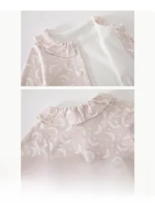 Detail of baby pink floral bodysuit featuring ruffled collar and delicate moon patterns