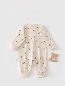 Detail of baby romper featuring orange and grey bird print on cream cotton fabric
