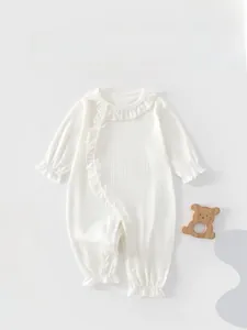 Detail of soft ribbed cotton baby romper with decorative ruffled edges and button closure
