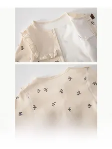 Detail of baby cotton romper with bird print, lace Peter Pan collar and soft texture