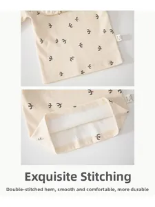 Détail du haut en coton pour bébé avec ourlet à double couture et motif oiseaux gris