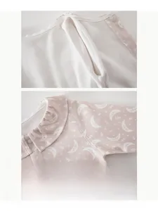 Detail of pink baby bodysuit with moon stars pattern and ruffled collar soft cotton fabric