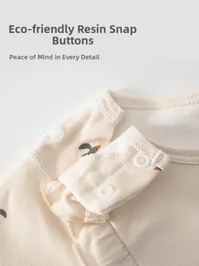 Detail view of baby bodysuit showing eco-friendly resin snaps and swallow print on cotton fabric