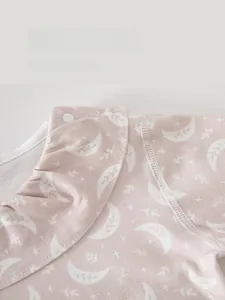 Detail of pink cotton baby pajamas featuring ruffled collar and eco-friendly resin buttons