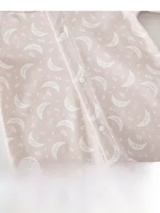 Close-up of pink baby romper fabric with moon and star print and white resin snap buttons