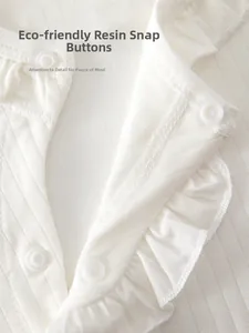 Detail of eco-friendly resin snap buttons and ruffled collar on cotton baby bodysuit