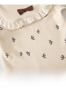 Détail d'ensemble bébé en coton avec imprimé hirondelle, col à volants et petit nœud