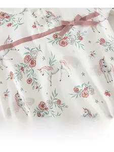 Detail of baby cotton bodysuit featuring unicorn floral print and pink bow decoration