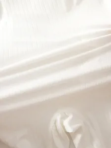 Close-up of soft white ribbed cotton fabric showing breathable knitting detail for babies