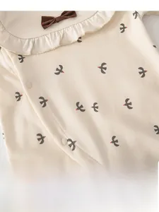 Close-up of baby romper featuring bird prints and elegant white ruffle collar detail