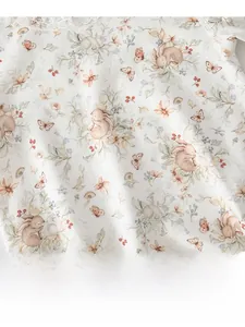 Gros plan sur l'imprimé lapin floral et le col en dentelle du body en coton bébé