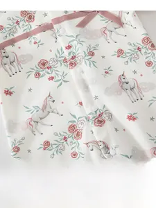 Detail of baby romper featuring floral unicorn print with snap buttons and bow accent