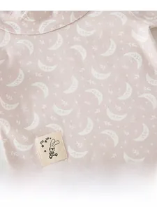 Detailed macro of pink cotton baby pajamas with moon stars print and Fly Up cloth patch