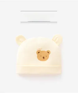 Detail of soft pale yellow newborn cotton hat featuring cute 3D bear ears and sweet print