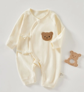 Detail of newborn cotton bodysuit with plush bear patch and side bow tie fastening